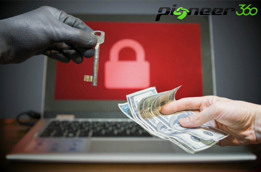 A person is holding money and another person is holding a key. In the background there is a laptop with a padlock on the screen.