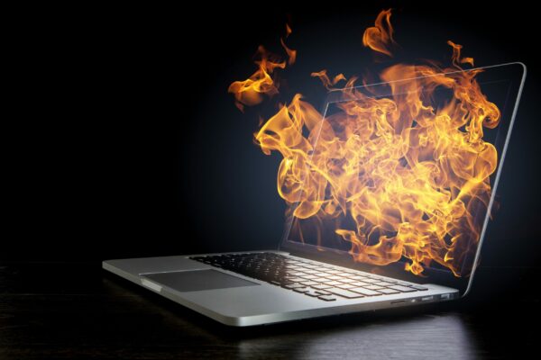 A laptop computer is on fire with flames coming out of it.