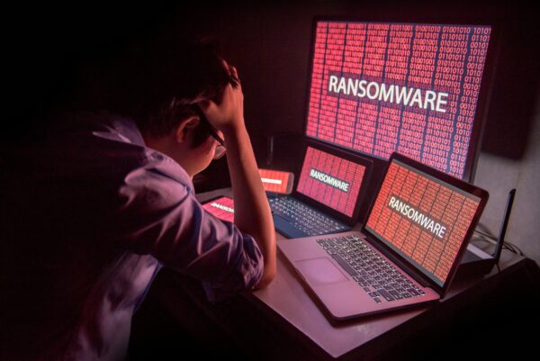 A man sitting in front of a laptop with the word 'ransomware' on it.