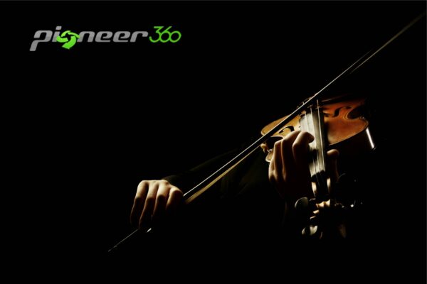 A man is playing a violin in a dark room.