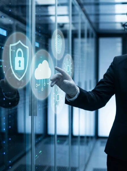 Person in a suit interacts with virtual cybersecurity icons, including a lock, cloud, fingerprint, and microchip, in a data center environment.