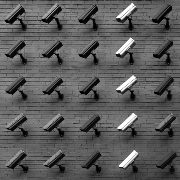 A black and white photo of cctv cameras on a wall.