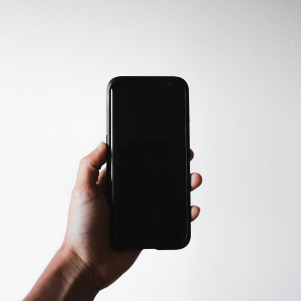 A hand holding a black smartphone against a white background.